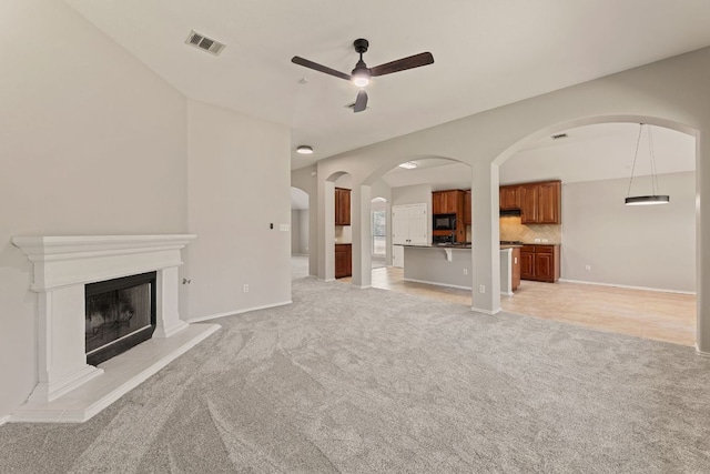 1129 Wigwam Dr, Leander, TX 78641 - unfurnished living room with a ceiling fan, light colored carpet, arched walkways, and a fireplace with raised hearth