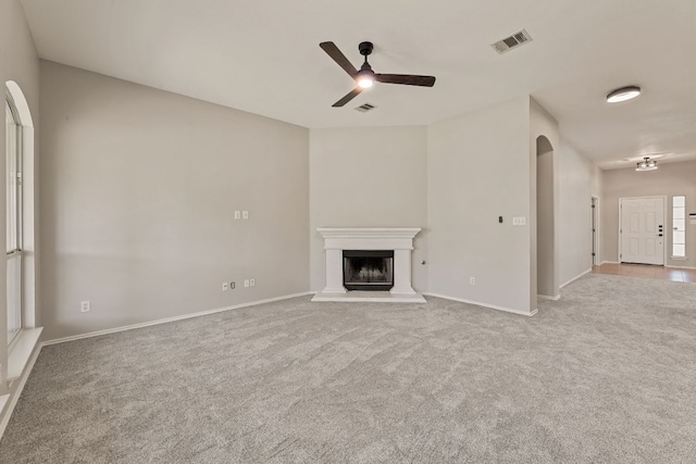 1129 Wigwam Dr, Leander, TX 78641 - unfurnished living room with a ceiling fan, carpet flooring, a fireplace with raised hearth, and arched walkways