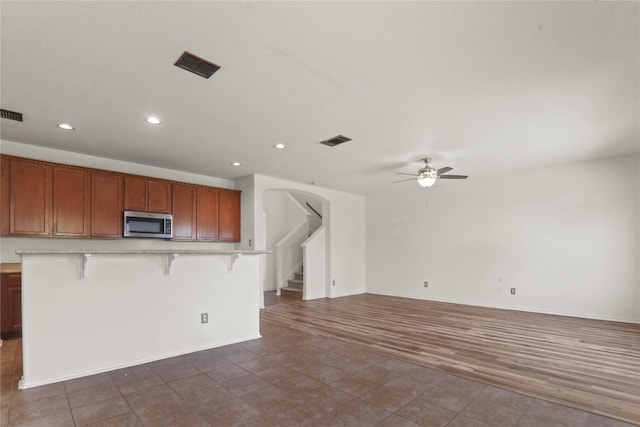 232 Wells Bnd, Hutto, TX 78634 - kitchen featuring stainless steel microwave, a ceiling fan, a breakfast bar area, recessed lighting, and light countertops