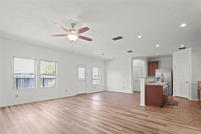 232 Wells Bnd, Hutto, TX 78634 - unfurnished living room with arched walkways, a ceiling fan, recessed lighting, light wood-type flooring, and baseboards