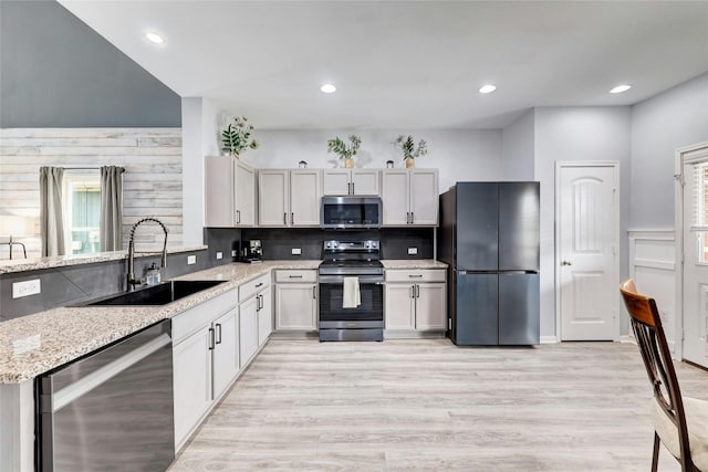 107 Denton Dr, Hutto, TX 78634 - kitchen with appliances with stainless steel finishes, light stone counters, decorative backsplash, light wood-type flooring, and recessed lighting