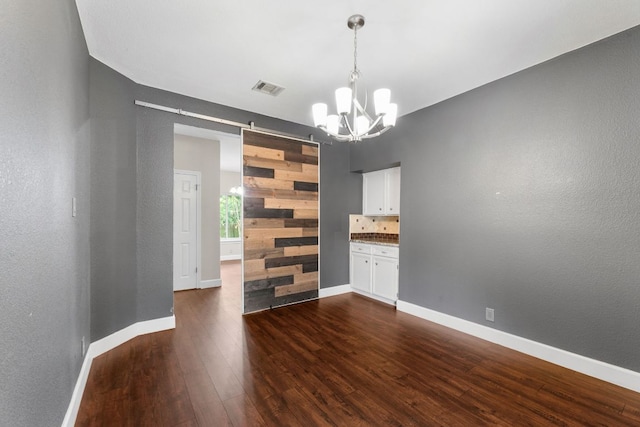 2308 Falcon Dr, Round Rock, TX 78681 - unfurnished room featuring a chandelier, dark wood-style floors, a barn door, baseboards, and a textured wall