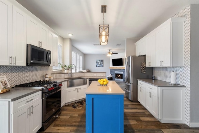320 Ranier Ln, Round Rock, TX 78665 - kitchen with black range with gas stovetop, a sink, ceiling fan, a lit fireplace, and tasteful backsplash
