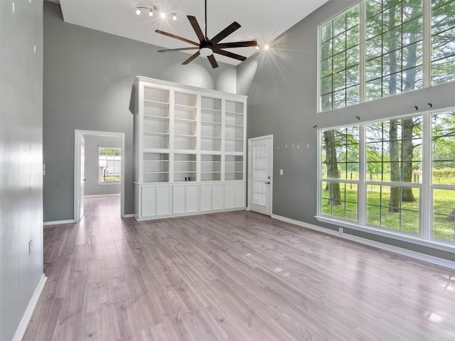 2939 Jeffcote Rd, Conroe, TX 77303 - unfurnished living room with a towering ceiling, ceiling fan, baseboards, and wood finished floors