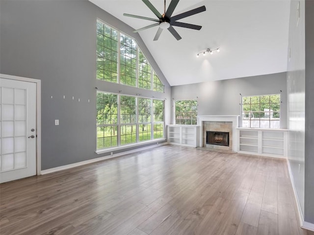 2939 Jeffcote Rd, Conroe, TX 77303 - unfurnished living room featuring high vaulted ceiling, a ceiling fan, a fireplace, healthy amount of natural light, and wood finished floors