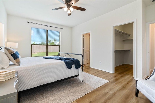 16513 Brogan Ln, Pflugerville, TX 78660 - bedroom featuring light wood-style floors, a spacious closet, baseboards, a closet, and a ceiling fan