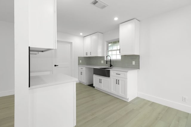 1509 Parkview Ln, San Marcos, TX 78666 - kitchen featuring a sink, light wood finished floors, light countertops, decorative backsplash, and white cabinetry