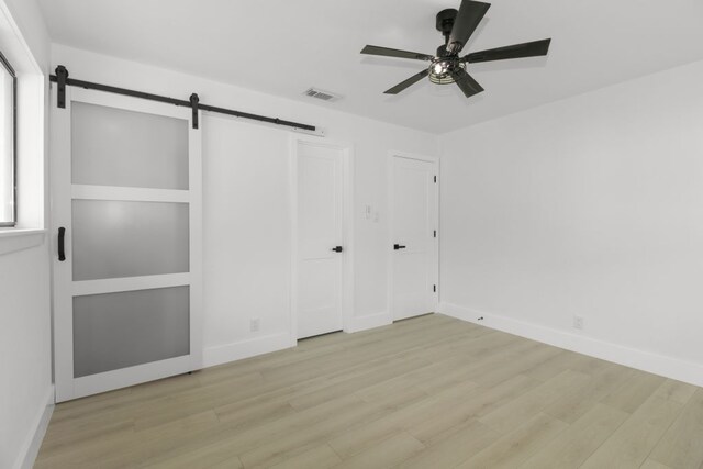 1509 Parkview Ln, San Marcos, TX 78666 - unfurnished bedroom with a barn door, wood finished floors, and baseboards