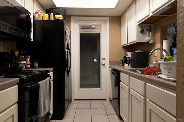 2625 Gwendolyn Ln, Austin, TX 78748 - kitchen with black appliances, a sink, light tile patterned floors, white cabinets, and a skylight