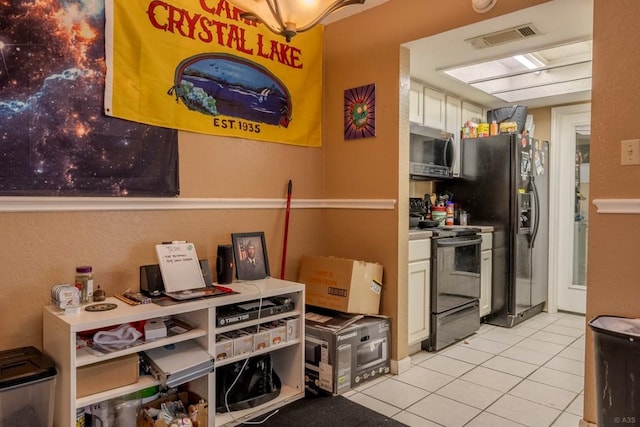 2625 Gwendolyn Ln, Austin, TX 78748 - kitchen with black appliances, light tile patterned floors, and white cabinetry
