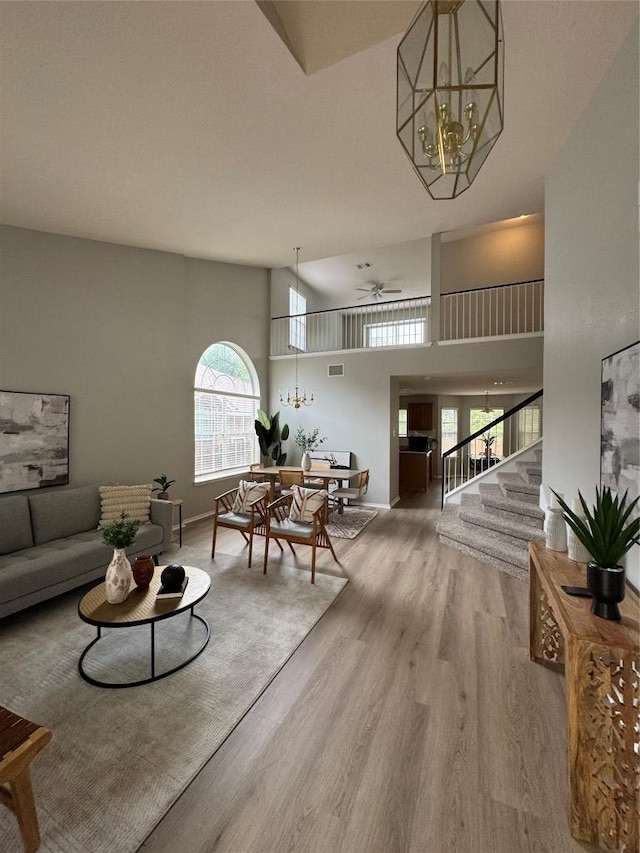10301 Beard Ave, Austin, TX 78748 - living area featuring stairs, wood finished floors, healthy amount of natural light, a ceiling fan, and a high ceiling