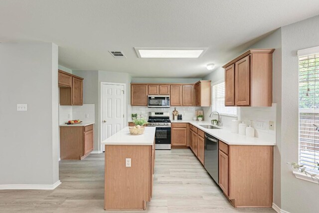 10301 Beard Ave, Austin, TX 78748 - kitchen featuring appliances with stainless steel finishes, light wood-type flooring, backsplash, and a kitchen island