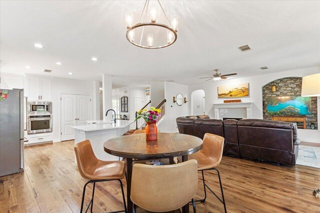 2713 Vaquera Ct, Round Rock, TX 78681 - dining space featuring a fireplace, light wood-type flooring, a chandelier, recessed lighting, and arched walkways