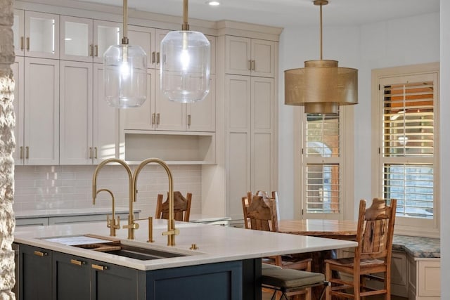 116 Horseshoe Dr, Dripping Springs, TX 78620 - kitchen with a sink, backsplash, hanging light fixtures, a kitchen island with sink, and white cabinets