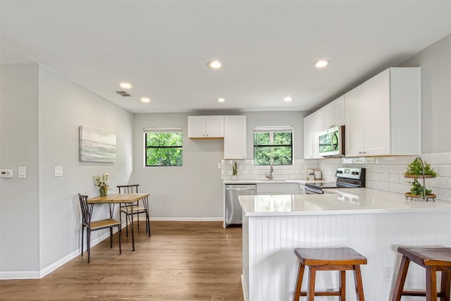 125 San Jacinto St, Bastrop, TX 78602 - kitchen featuring stainless steel appliances, wood finished floors, a peninsula, decorative backsplash, and recessed lighting