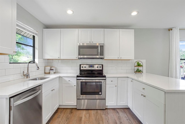 125 San Jacinto St, Bastrop, TX 78602 - kitchen with stainless steel appliances, a sink, a peninsula, light countertops, and white cabinetry