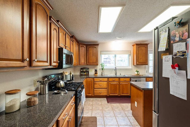 1202 Tremont Dr, Cedar Park, TX 78613 - kitchen featuring appliances with stainless steel finishes, a sink, brown cabinetry, a textured ceiling, and light tile patterned floors