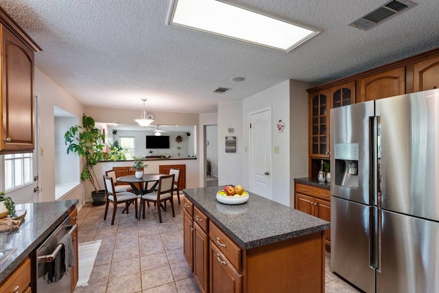 1202 Tremont Dr, Cedar Park, TX 78613 - kitchen with stainless steel appliances, glass insert cabinets, brown cabinetry, a center island, and a textured ceiling