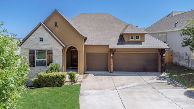 18716 Waltz Ct, Austin, TX 78738 - french provincial home featuring stone siding, a garage, concrete driveway, and roof with shingles