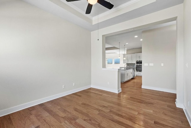 18716 Waltz Ct, Austin, TX 78738 - unfurnished living room featuring ceiling fan, ornamental molding, wood finished floors, baseboards, and a raised ceiling