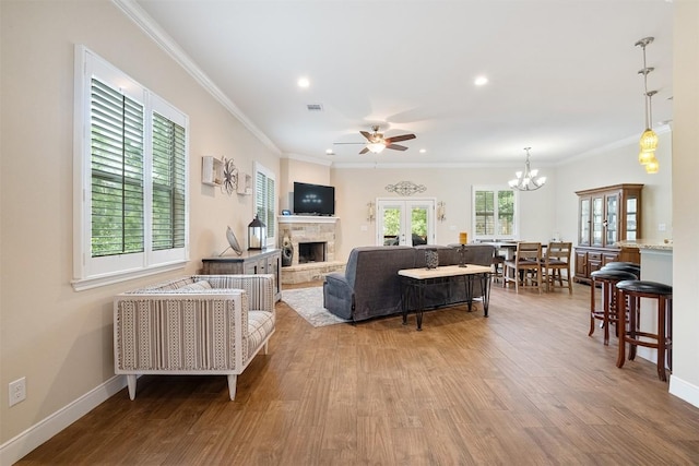 108 Kaliu Ct, Bastrop, TX 78602 - living room featuring wood finished floors, ceiling fan, a stone fireplace, ornamental molding, and recessed lighting