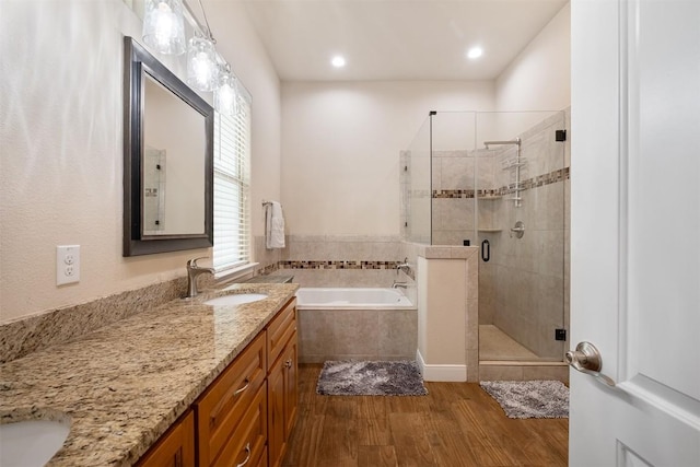 108 Kaliu Ct, Bastrop, TX 78602 - full bathroom with vanity, a garden tub, a shower stall, wood finished floors, and recessed lighting