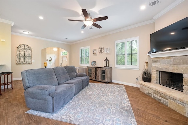108 Kaliu Ct, Bastrop, TX 78602 - living room with ornamental molding, ceiling fan, arched walkways, wood finished floors, and a stone fireplace