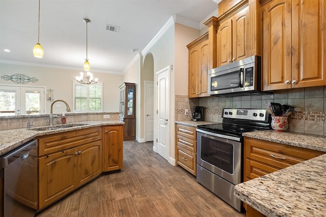 108 Kaliu Ct, Bastrop, TX 78602 - kitchen featuring stainless steel appliances, ornamental molding, light stone counters, backsplash, and dark wood-style flooring
