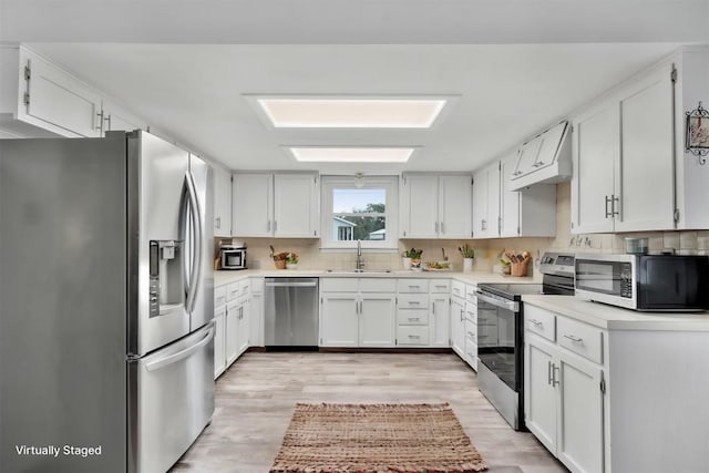 283 Rockdale W Rd, Rockdale, TX 76567 - kitchen with stainless steel appliances, a sink, custom exhaust hood, backsplash, and white cabinetry