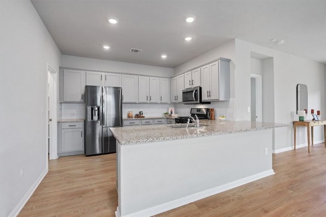 632 Otto Ave, Georgetown, TX 78626 - kitchen featuring appliances with stainless steel finishes, light wood-type flooring, light stone counters, a peninsula, and recessed lighting