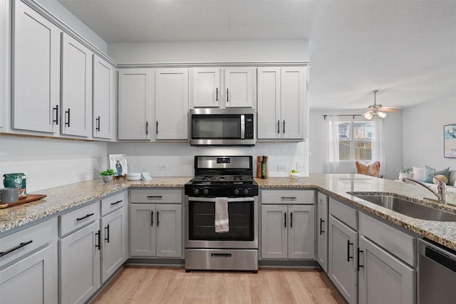 632 Otto Ave, Georgetown, TX 78626 - kitchen featuring stainless steel appliances, gray cabinetry, light wood-type flooring, a ceiling fan, and light stone countertops