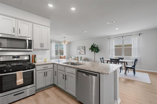632 Otto Ave, Georgetown, TX 78626 - kitchen with stainless steel appliances, a peninsula, light wood finished floors, light stone countertops, and recessed lighting