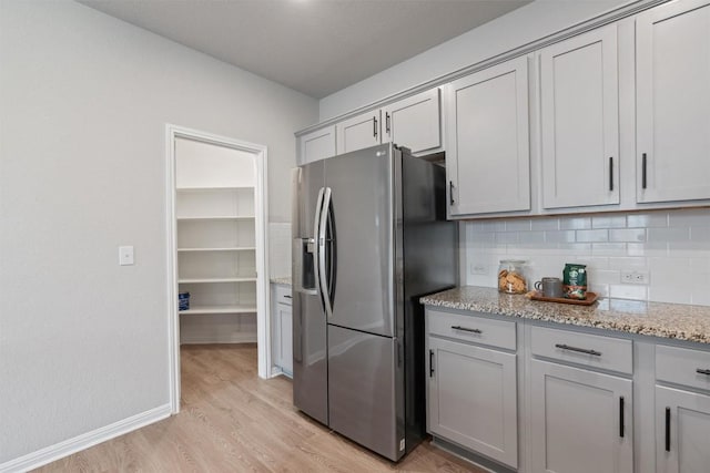 632 Otto Ave, Georgetown, TX 78626 - kitchen with stainless steel fridge with ice dispenser, light wood-style flooring, gray cabinets, tasteful backsplash, and light stone counters