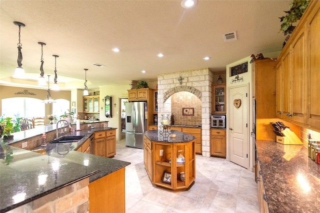 1265 Mourning Dove Ct, Salado, TX 76571 - kitchen with stainless steel fridge with ice dispenser, a large island with sink, a sink, brown cabinetry, and recessed lighting