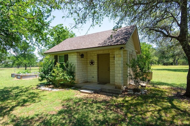 1265 Mourning Dove Ct, Salado, TX 76571 - view of front of home with a vegetable garden, a front lawn, a shingled roof, and an outdoor structure
