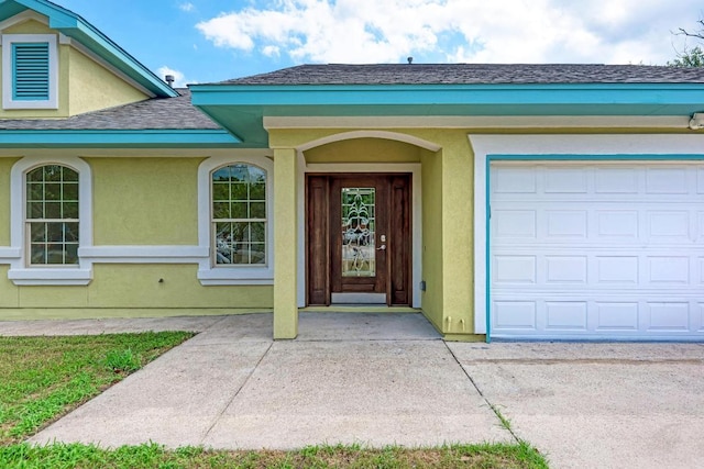 903 N Neans Dr, Austin, TX 78758 - view of exterior entry featuring stucco siding, a shingled roof, a garage, and driveway