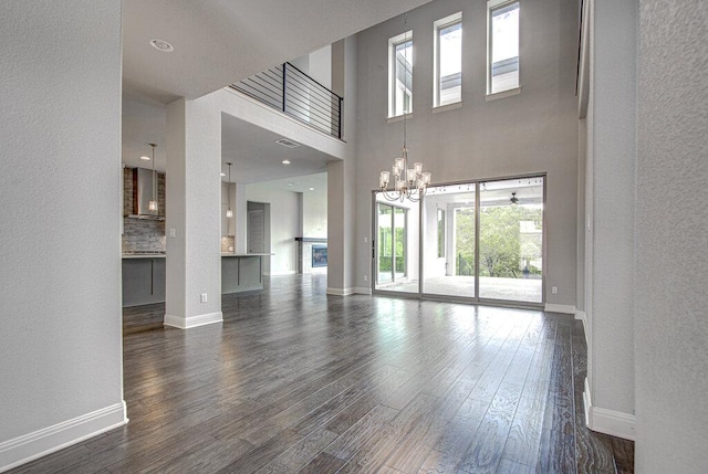1916 Port Bari Ct, Leander, TX 78641 - unfurnished living room featuring dark wood-style flooring, baseboards, a chandelier, a textured wall, and a high ceiling