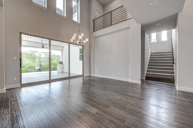 1916 Port Bari Ct, Leander, TX 78641 - unfurnished living room featuring healthy amount of natural light, a chandelier, dark wood-style flooring, stairs, and a towering ceiling