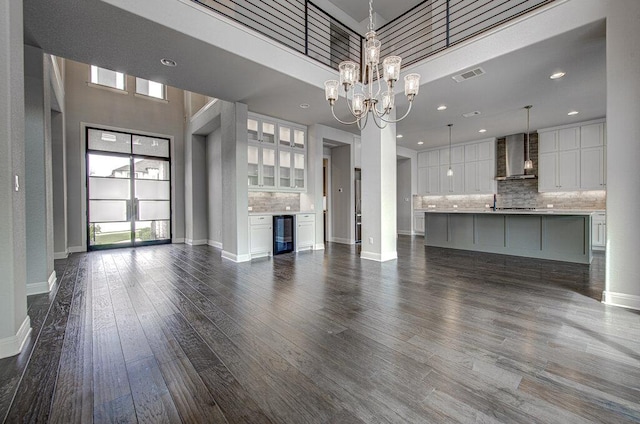 1916 Port Bari Ct, Leander, TX 78641 - unfurnished living room featuring a chandelier, dark wood finished floors, baseboards, wine cooler, and a towering ceiling