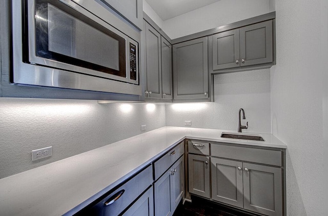 1916 Port Bari Ct, Leander, TX 78641 - kitchen featuring stainless steel microwave, gray cabinets, a sink, and light countertops