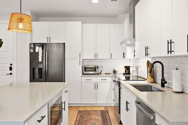 3101 Govalle Ave Unit 219, Austin, TX 78702 - kitchen with stainless steel appliances, a sink, wall chimney exhaust hood, light wood-style floors, and decorative backsplash
