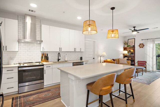 3101 Govalle Ave Unit 219, Austin, TX 78702 - kitchen with stainless steel appliances, wall chimney exhaust hood, a sink, light wood finished floors, and recessed lighting