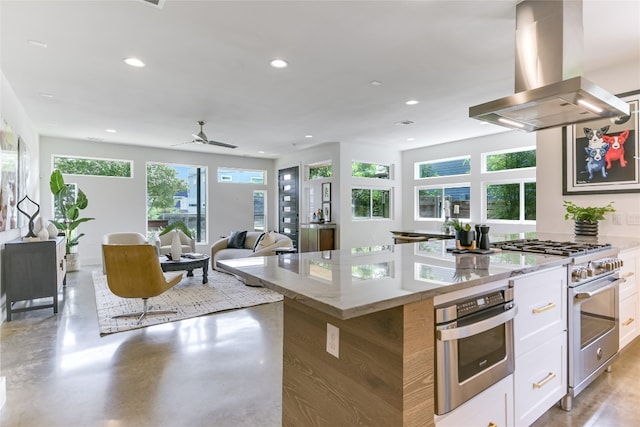1904 Sl Davis Ave Unit 1, Austin, TX 78702 - kitchen featuring island exhaust hood, stainless steel appliances, plenty of natural light, white cabinetry, and recessed lighting