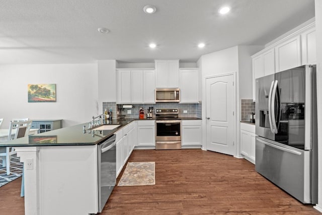 7212 Summer Tanager Dr Unit 28, Austin, TX 78744 - kitchen with stainless steel appliances, dark countertops, a peninsula, dark wood-style flooring, and decorative backsplash