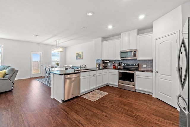 7212 Summer Tanager Dr Unit 28, Austin, TX 78744 - kitchen featuring appliances with stainless steel finishes, open floor plan, a peninsula, tasteful backsplash, and dark countertops