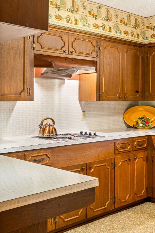 3503 Carla Dr, Austin, TX 78754 - kitchen with under cabinet range hood, light countertops, decorative backsplash, and brown cabinetry