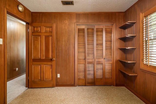 3503 Carla Dr, Austin, TX 78754 - unfurnished bedroom with wooden walls, a textured ceiling, a closet, multiple windows, and carpet