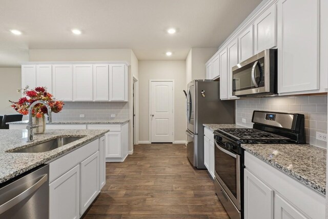 408 Rainmaker Ln, Bastrop, TX 78602 - kitchen featuring stainless steel appliances, a sink, white cabinets, decorative backsplash, and recessed lighting