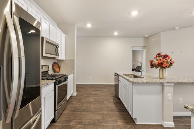 408 Rainmaker Ln, Bastrop, TX 78602 - kitchen featuring stainless steel appliances, a sink, tasteful backsplash, a kitchen island with sink, and white cabinetry