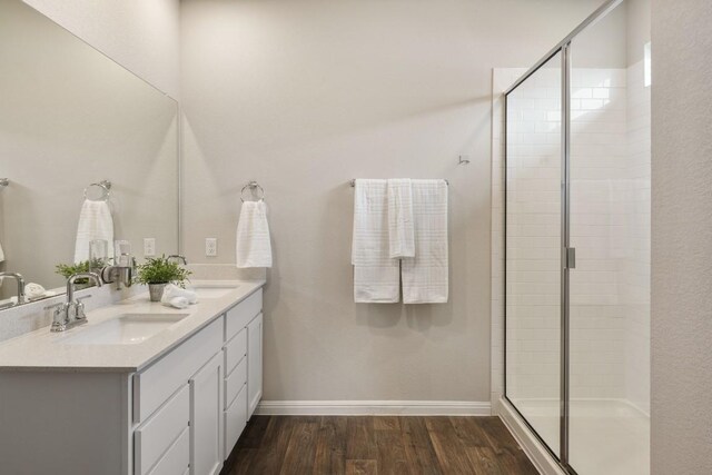 408 Rainmaker Ln, Bastrop, TX 78602 - bathroom featuring double vanity, wood finished floors, a shower stall, and baseboards